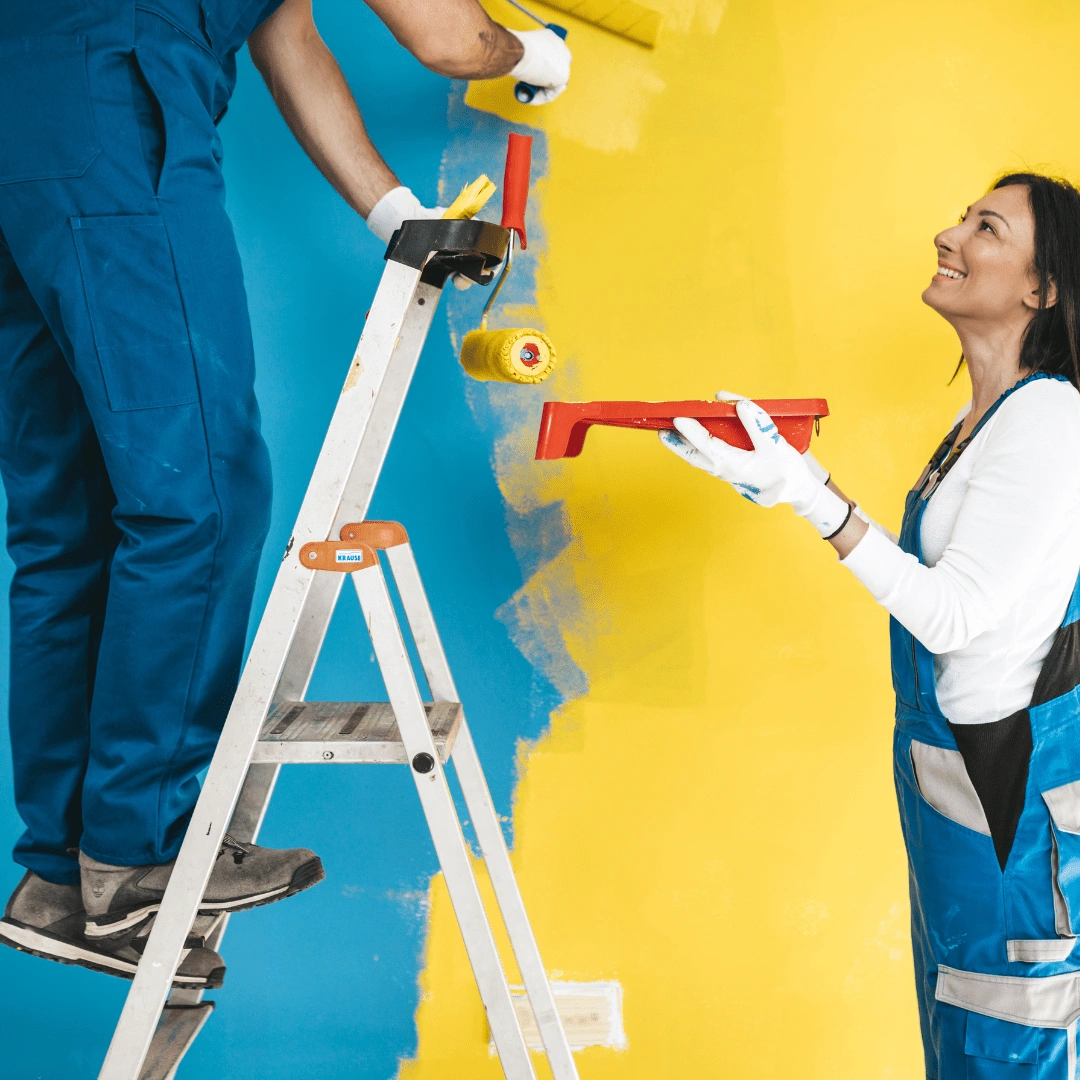 A image of man painting wall with roller, woman assisting with paint tray.